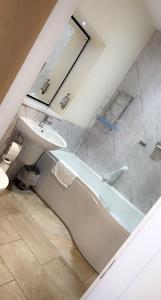 StranocumThe Hedges Hotel的一间带水槽、浴缸和卫生间的浴室