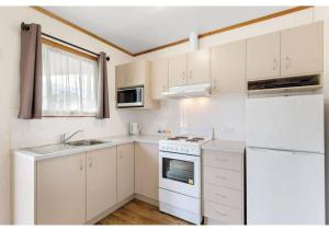 科芬贝Discovery Parks - Coffin Bay的厨房配有白色橱柜、水槽和冰箱。