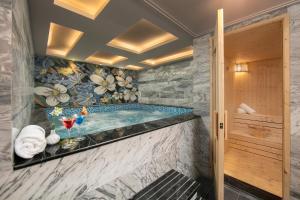 河内Anatole Hotel Hanoi的浴室设有按摩浴缸,装饰有花卉壁纸