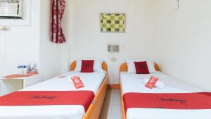 HamticRedDoorz @ Golden Travellers Inn Antique的配有红色和白色床单的客房内的两张床