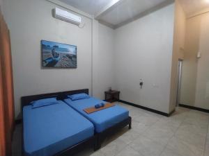巴芝丹Bintang Homestay Watukarung的卧室配有蓝色的床,墙上挂着一幅画