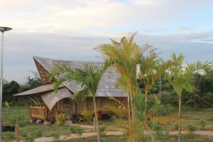 磅湛Hanchey Bamboo Resort的棕榈树旁的茅草屋顶小房子