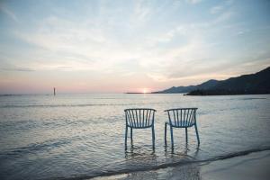 出云市Jikukan Mukae的两把椅子坐在海滩的水里