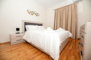 塞萨洛尼基Central Luxury Apartment的白色的卧室设有一张白色的大床和木地板