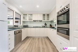 格罗夫海洋Ocean Grove Beach House的厨房配有白色橱柜和不锈钢用具