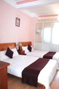 大叻New Sleep in Dalat Hostel的酒店客房设有两张床和窗户。