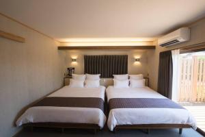 出云市Jikukan Enishi的配有窗户的酒店客房内的两张床