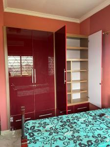 库马西OKF OBOUBA APARTMENT的卧室拥有红色的墙壁,配有一张床和架子