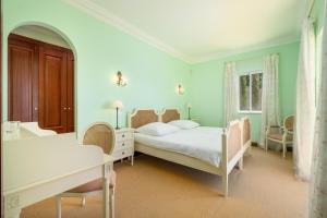 丰沙尔Palheiro Village - Golf, Gardens & Spa的一间卧室配有一张床、一张桌子和一张桌子