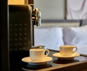 十月六日城Crowne Plaza - West Cairo Arkan, an IHG Hotel的两杯咖啡,放在带咖啡机的柜台上