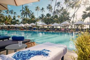 普瓦尼梅查恩加尼TUI BLUE Bahari Zanzibar的度假酒店的游泳池配有椅子和遮阳伞
