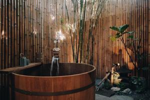 曼谷MAYU Bangkok Japanese Style Hotel的竹墙前的浴缸及喷泉