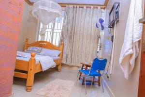 坎帕拉Precise Motel的一间卧室配有木床和蓝椅