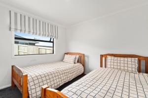 陶波Puna Rise - Taupo Holiday Home的带窗户的客房内的两张床