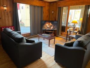 梅干提克湖Auberge et Chalets sur le Lac的客厅设有两张沙发和一个壁炉
