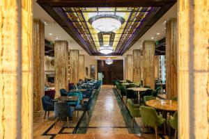 兹拉蒂博尔A Hoteli - Grand&Sky Hotel Tornik的一间带桌椅的用餐室和彩色玻璃天花板