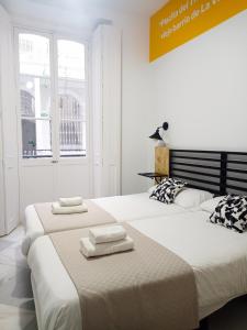 加的斯Planeta Cadiz Hostel的白色客房内的两张床和毛巾