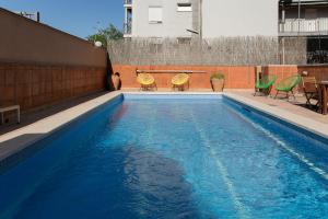 卡斯特尔德费尔斯Canela Homes COSTA CASA AILA的一个带蓝色海水和绿色椅子的游泳池
