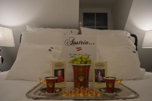 Lind ob Velden白宫奥地利公寓的床上的水果盘和两个杯子
