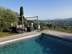 格拉斯Les lodges de l'oliveraie de Virevent的一个带椅子的游泳池和一个凉亭