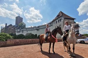 艾森纳赫Schöne Ferienwohnung „Zum Glück“的两个在城堡前骑着马的妇女