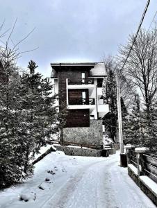 锡纳亚Casa Larisa - Wolves Apartment的一条有雪覆盖的道路,后面有一座建筑