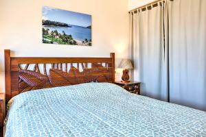 利胡埃Pristine Lihue Condo with Balcony Walk to Beach!的一间卧室设有蓝色的床和窗户。