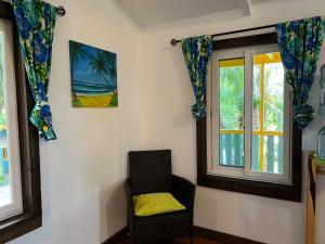 库尔克岛Colinda Cabanas的一间带椅子和两个窗户的房间
