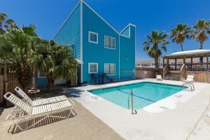 帕德雷岛Corpus Christi-Padre Island condo is walking distance to beach by Mustang Island, Sleeps Four, 2024 Traveler Award的一个带躺椅的游泳池以及一间蓝色的房子