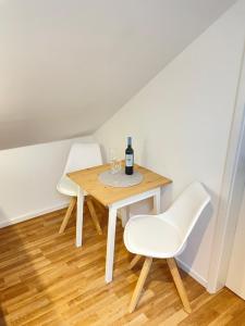 柏林Westendperle am Olympiastadion的一张桌子、两把白色椅子和一瓶葡萄酒
