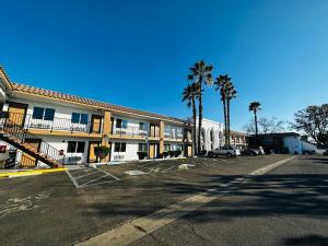 赛普里斯Casa Blanca Express & Suites Cypress Buena Park - Anaheim Area的棕榈树酒店前的停车场