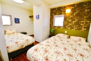 那霸Chura Gahna House Tsubogawa Naha的一间卧室设有两张床和砖墙