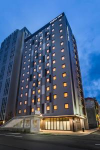 札幌Sotetsu Fresa Inn Sapporo-Susukino的一座黑色的大建筑,街上有很多窗户