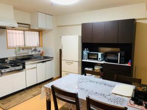 东京K&M Heights - Vacation STAY 32220v的厨房配有桌子和白色冰箱。