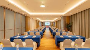 临沂市临沂滨河智选假日酒店的一间会议室,配有蓝色的桌子和白色的椅子