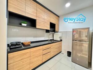 马六甲Bali Residence Melaka By Heystay Management的厨房配有木制橱柜和不锈钢冰箱。