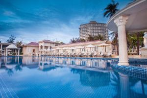 头顿The IMPERIAL Vung Tau Hotel的一个带椅子的游泳池和一个背景建筑