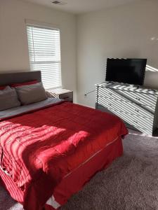 哥伦比亚SC 3745 New Townhouse Ft Jackson & USC的一间卧室配有红色的床和一台平面电视