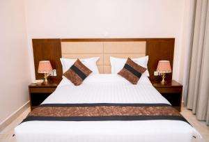 基加利Madras Hotel and Apartments的一间卧室配有一张带两盏灯的大型白色床。