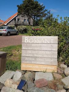 OosterendDe Oostkamer; Eiland appartement naast natuurgebied Boschplaat的一块房子后面的岩石上的标志