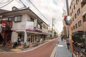 东京ミニマリズムホテル葛飾的一条街道上,有建筑,人走在人行道上