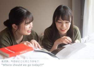 金泽LINNAS Kanazawa的坐在桌子旁读书的两位女士