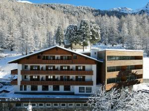 索尔达Hotel Mignon的雪地中的一座建筑,有雪覆盖的树木
