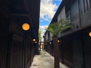 京都Rinn Shiki Juraku的两座建筑之间的小巷里棕榈树