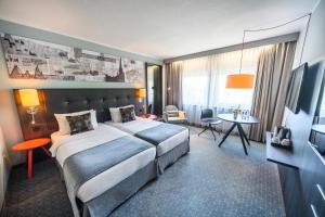 吕贝克Holiday Inn Lübeck, an IHG Hotel的酒店客房设有一张大床和一张桌子。