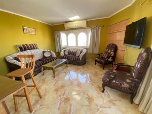 沙姆沙伊赫Al Crown的客厅配有沙发、椅子和电视