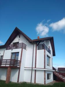 PrejmerVila Sol的白色的房子,设有木制阳台