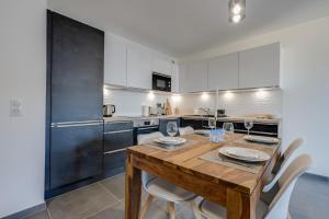 安锡Le Paradis - Beautiful T2 ideally located with garage的厨房配有木桌和白色橱柜。