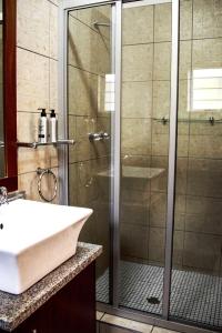 克龙斯塔德Kroon Manor的带淋浴和白色盥洗盆的浴室