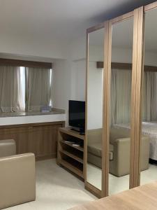 巴西利亚Flat hotel saint moritz的一间卧室配有一张床、一台电视和一面镜子